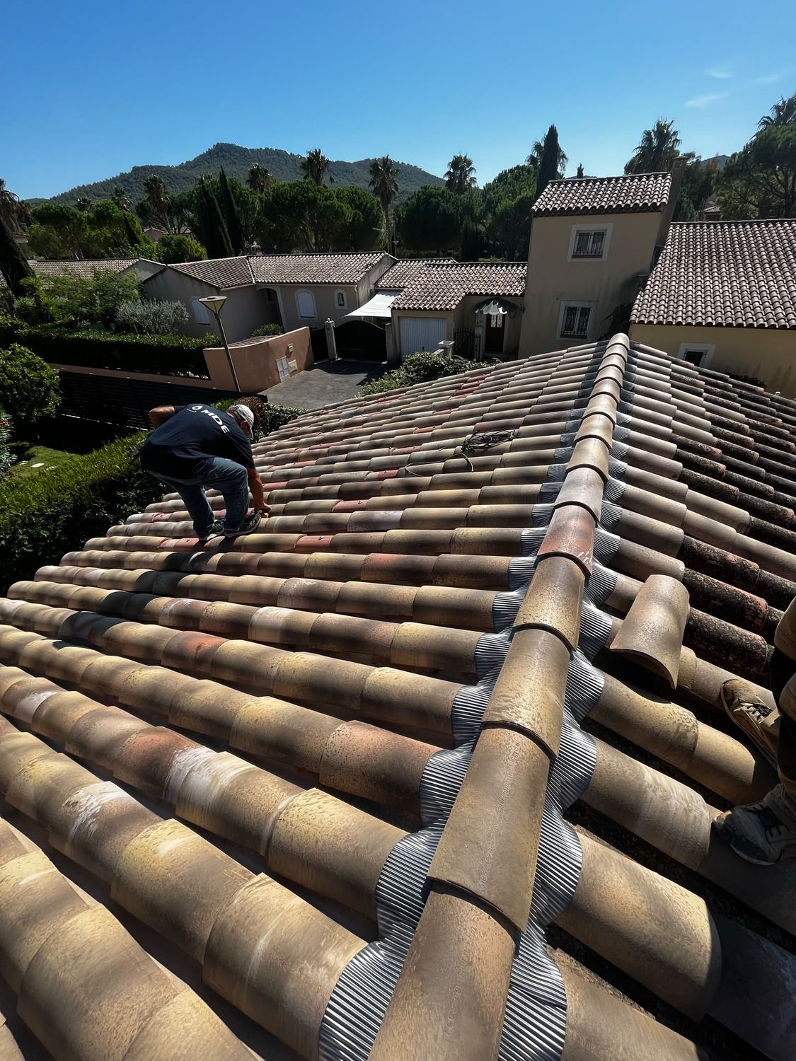 Couvreur au travail sur une toiture en tuiles canal